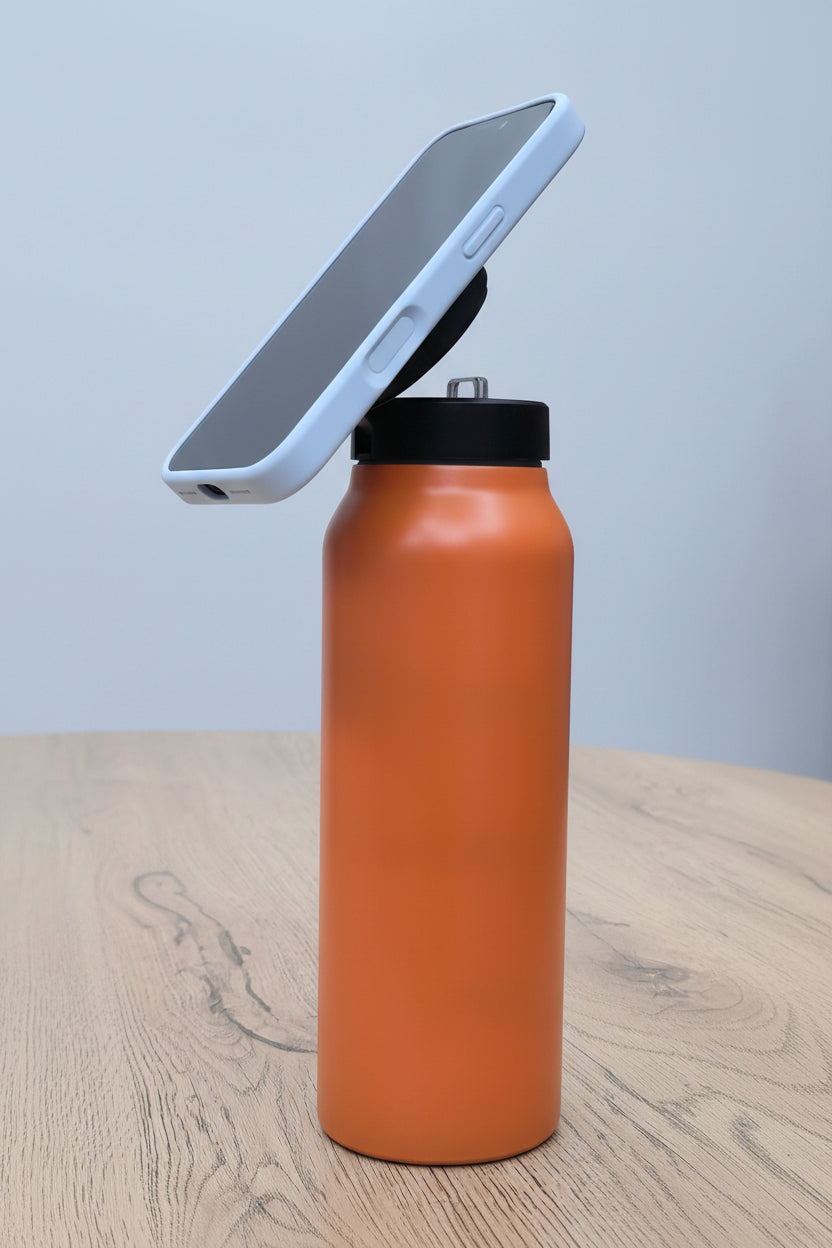 Termo isotérmico naranja con celular en soporte magnético - vista frontal sobre mesa