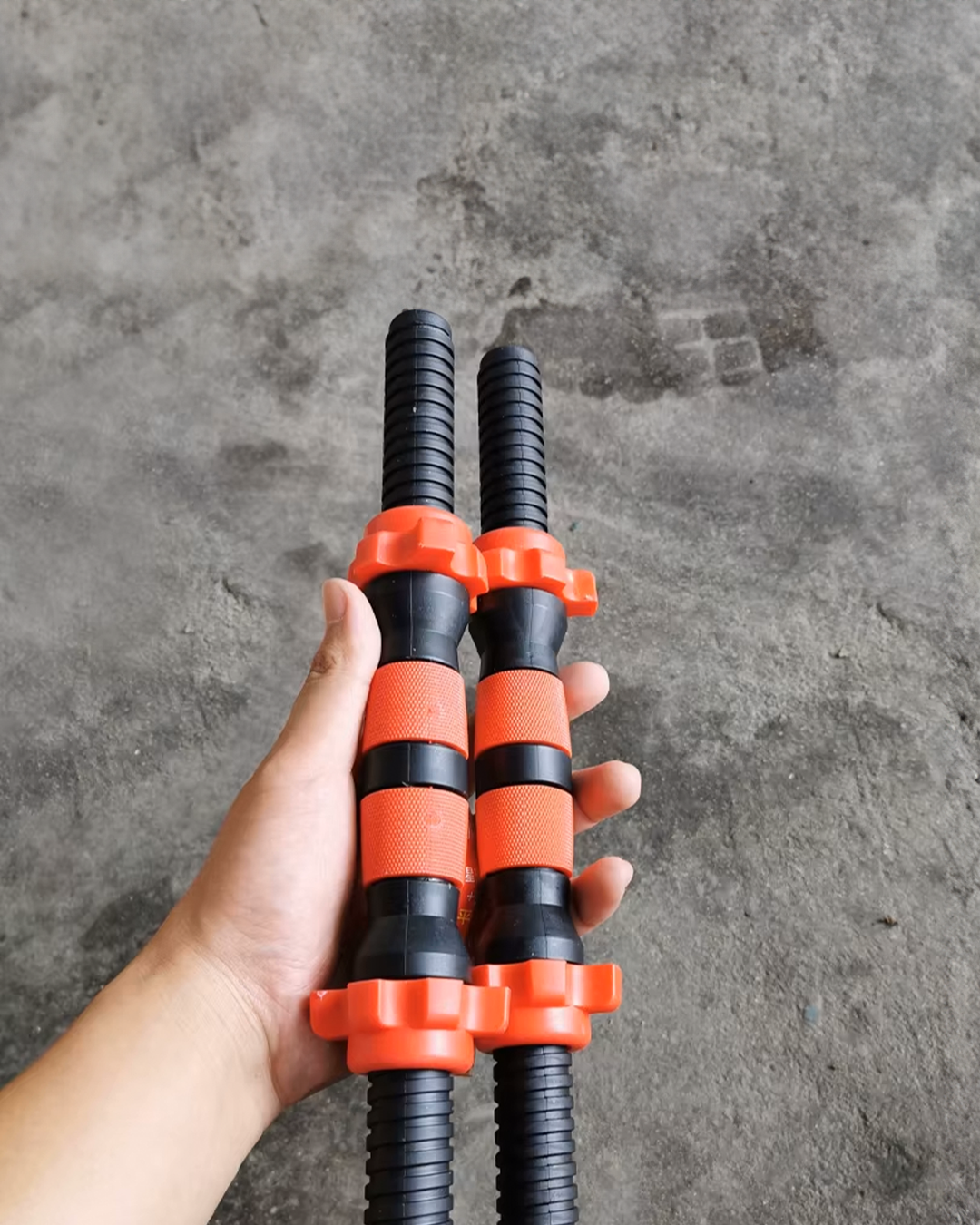 Mancuernas ajustables compactas con mango negro, bloques naranjas y discos
